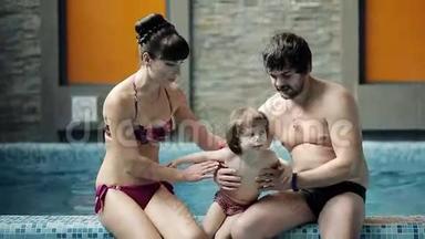 泳池里的年轻家庭。 父母带着儿子在游泳池里游泳和玩耍。